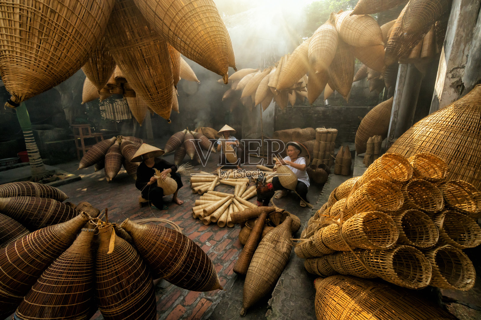 在越南红Yen Thu sy贸易村的老房子里，一群老越南女工匠正在制作传统的竹鱼陷阱或编织，这是传统的艺术家概念照片摄影图片