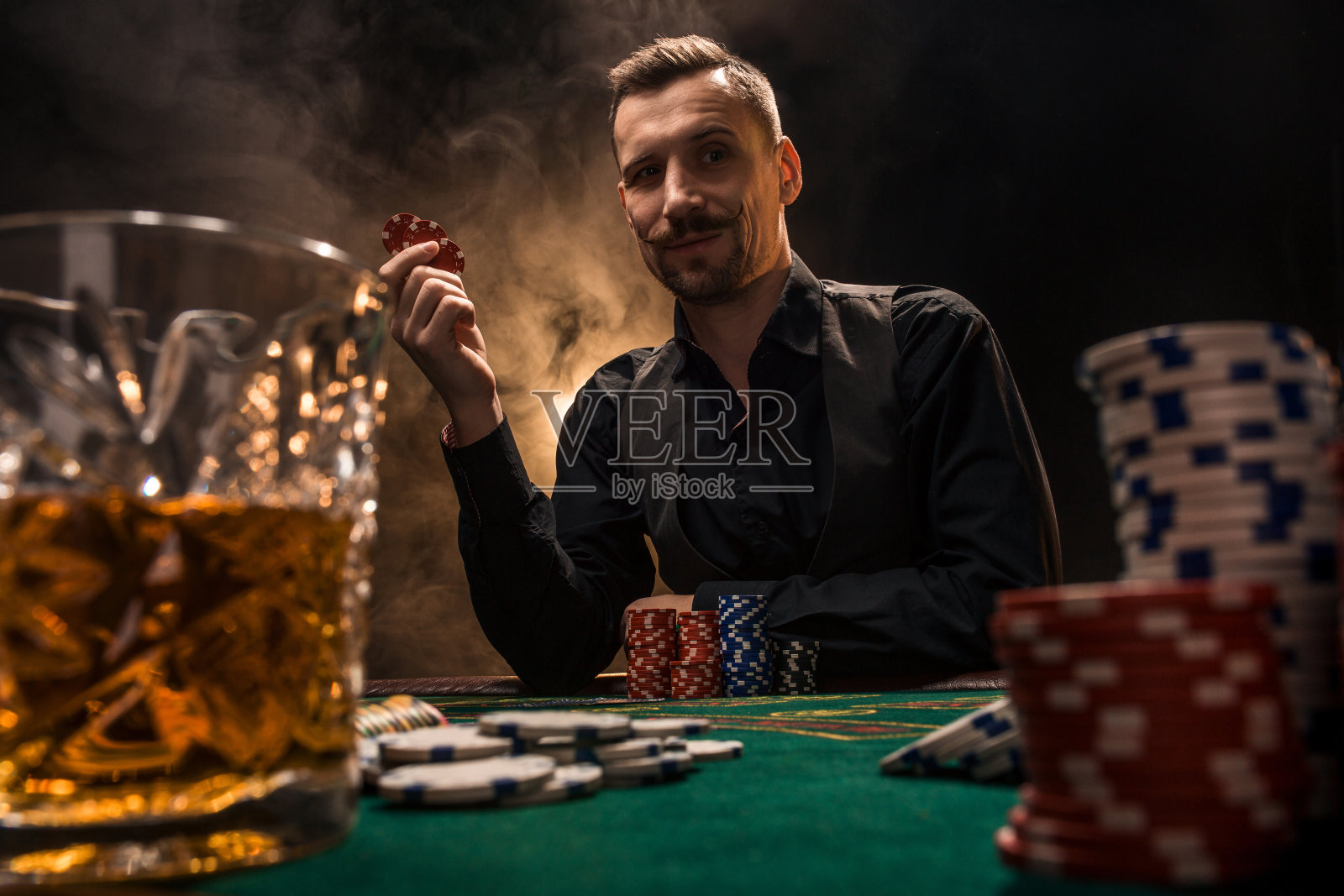 男人在玩扑克，抽着雪茄，喝着威士忌。一个用浓浓的香烟烟雾赢了桌上所有筹码的人照片摄影图片