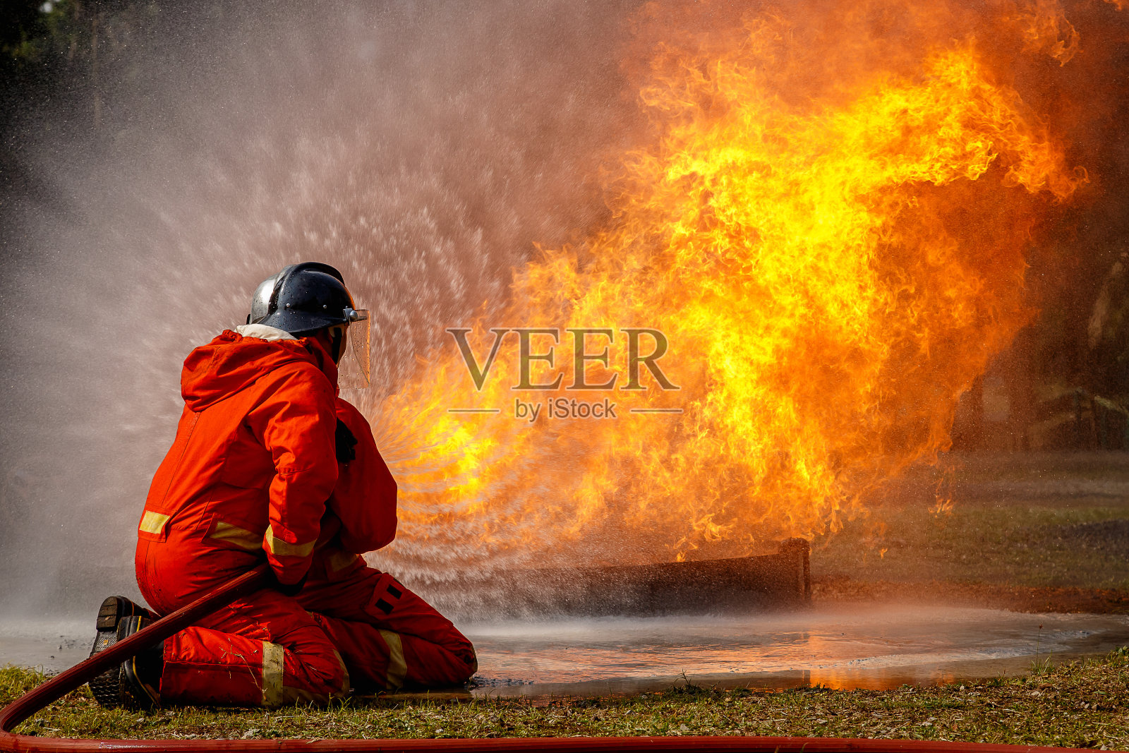 消防队员在灭火行动中，水被高压喷嘴喷到火焰周围，烟雾缭绕，消防队员扑灭一所房子照片摄影图片