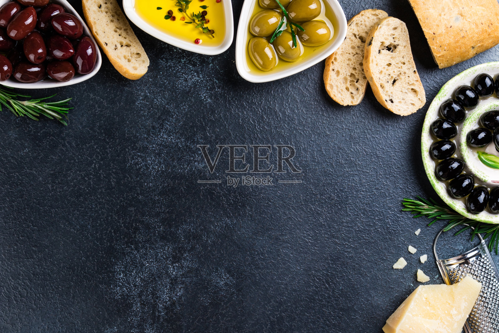 橄榄，夏巴塔面包，奶酪，油，香草和香料在黑色的石头背景。地中海的零食。开胃菜gourman食物。本空间照片摄影图片