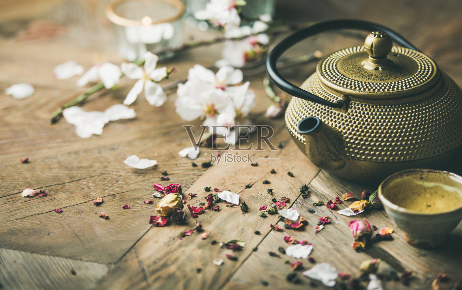 铁壶，茶杯，干玫瑰花蕾，盛开的杏花，蜡烛照片摄影图片