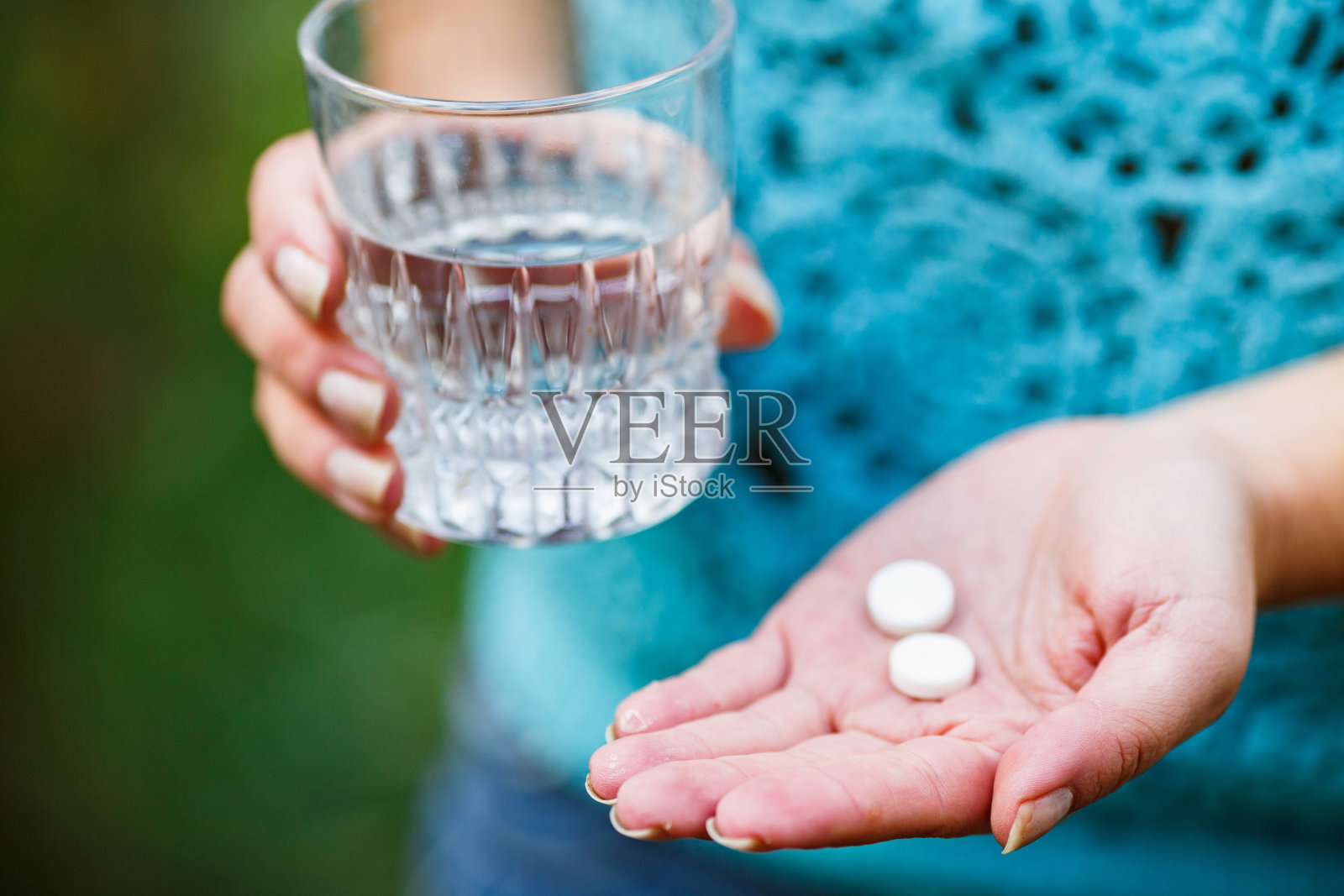 女孩拿着一杯清水和两粒白色药丸照片摄影图片