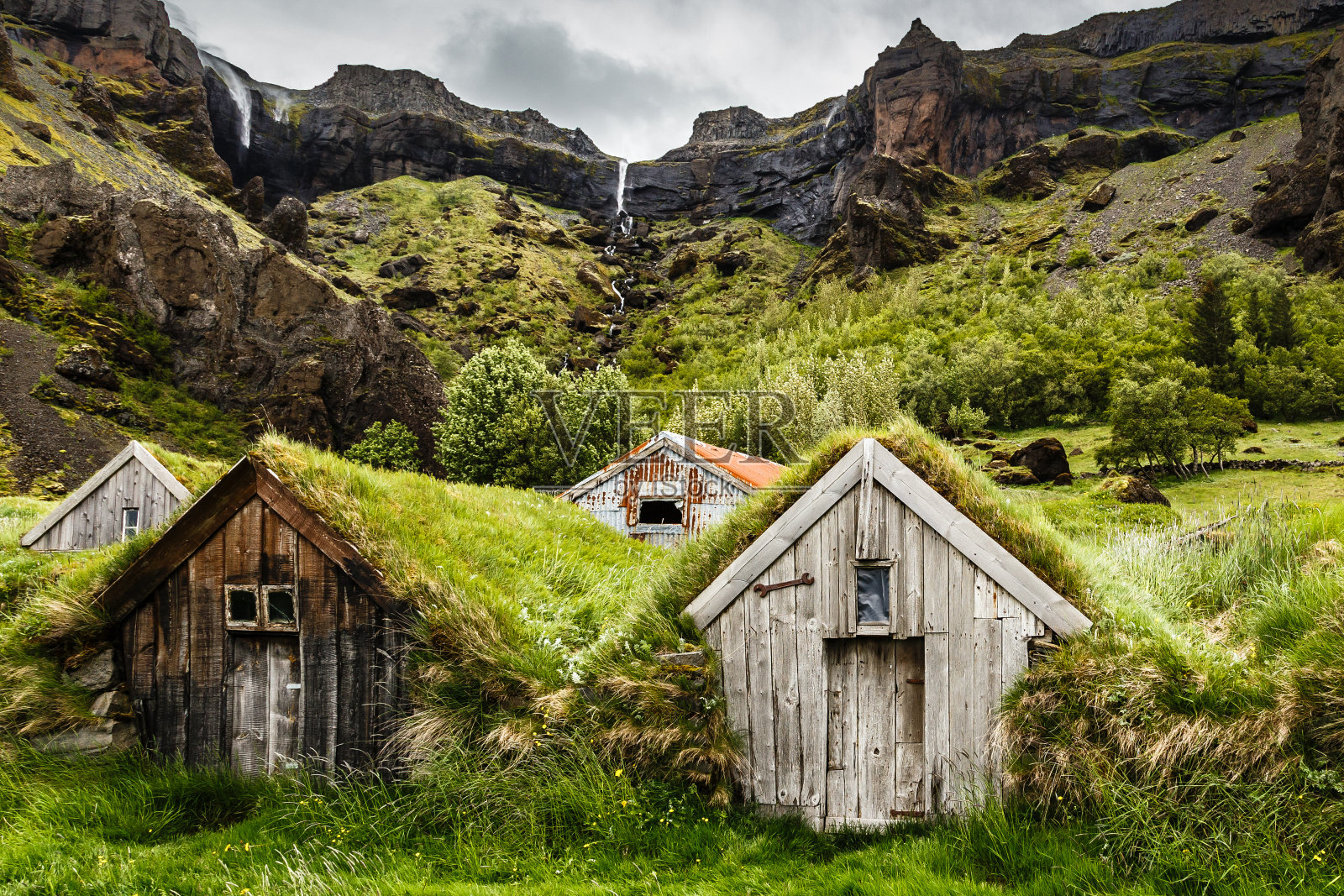 冰岛南部卡尔法费尔村附近的冰岛草皮屋和岩石峡谷，背景是瀑布照片摄影图片