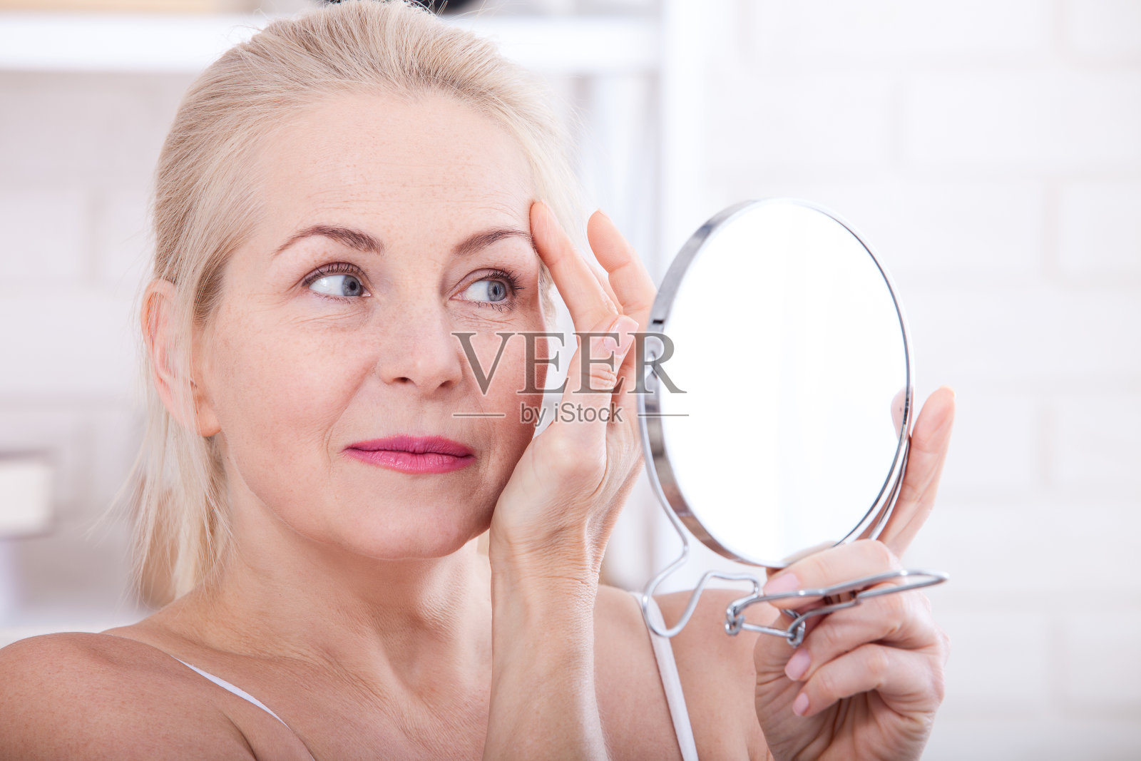 一个四十岁的女人在镜子里看着皱纹。整形手术和胶原蛋白注射。化妆。宏的脸。有选择性的重点照片摄影图片