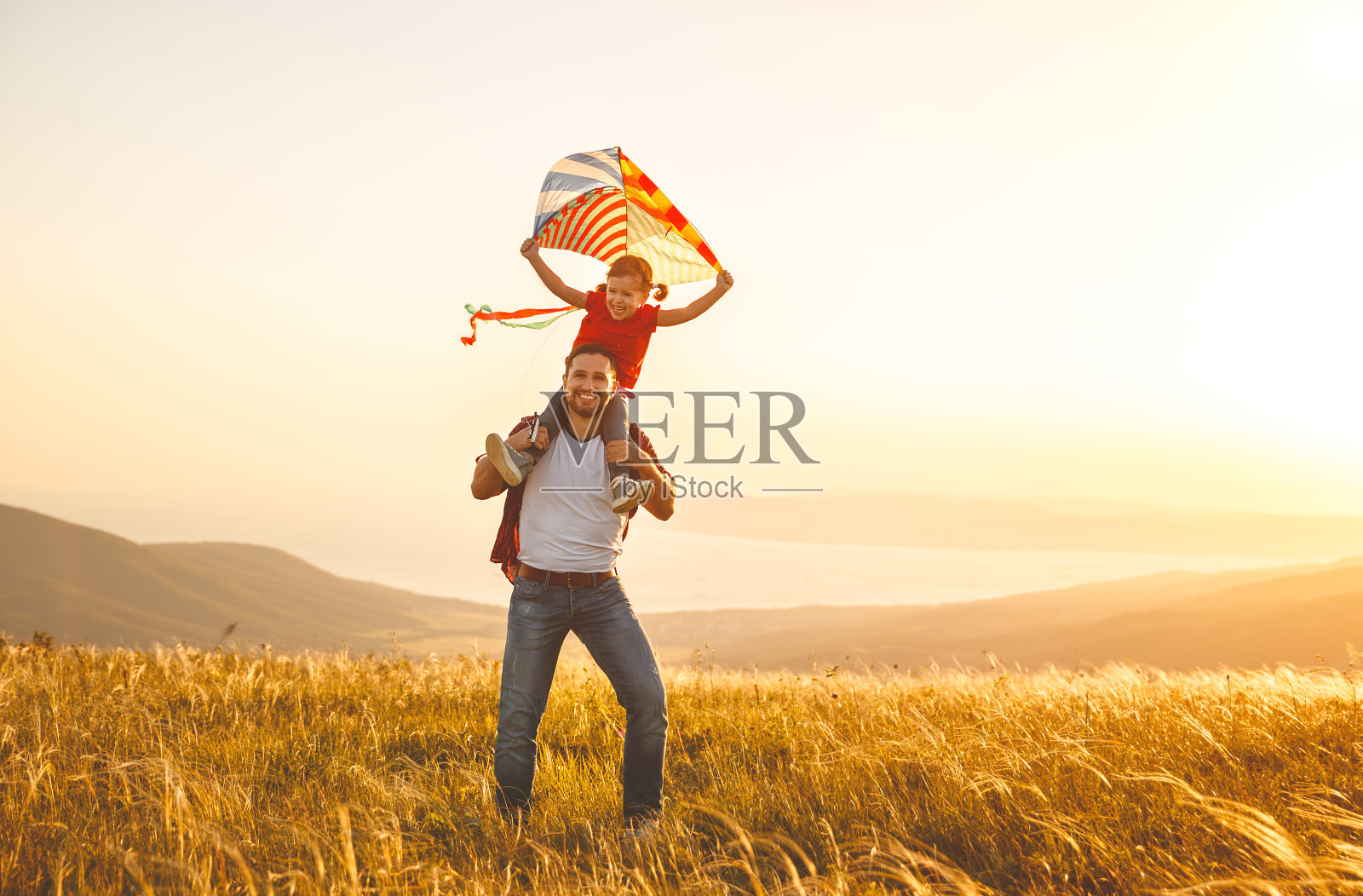 幸福的家庭，父亲和孩子女儿在草地上追风筝照片摄影图片