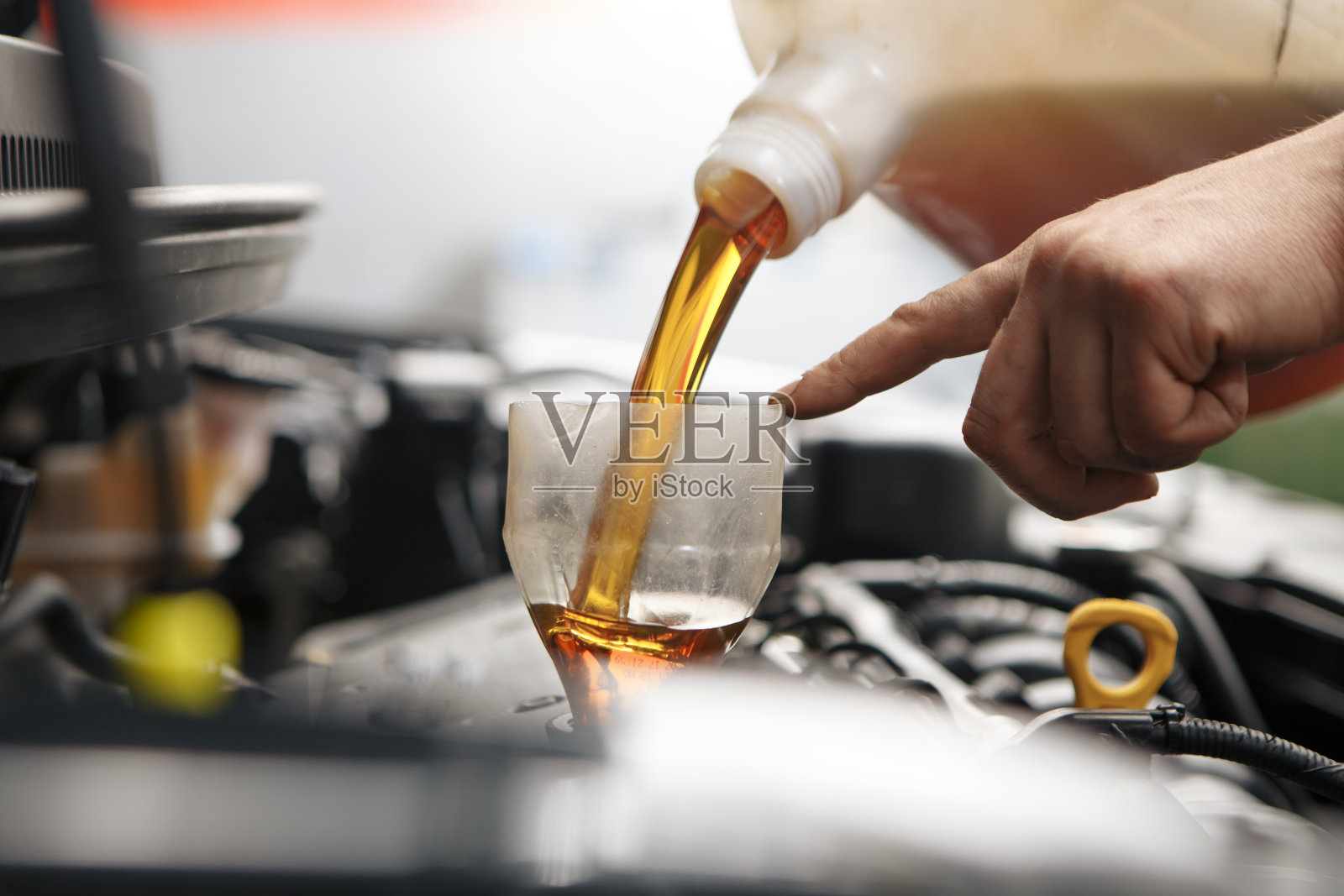 在汽车车间维修服务站为汽车发动机更换机油的专业汽车技师。照片摄影图片