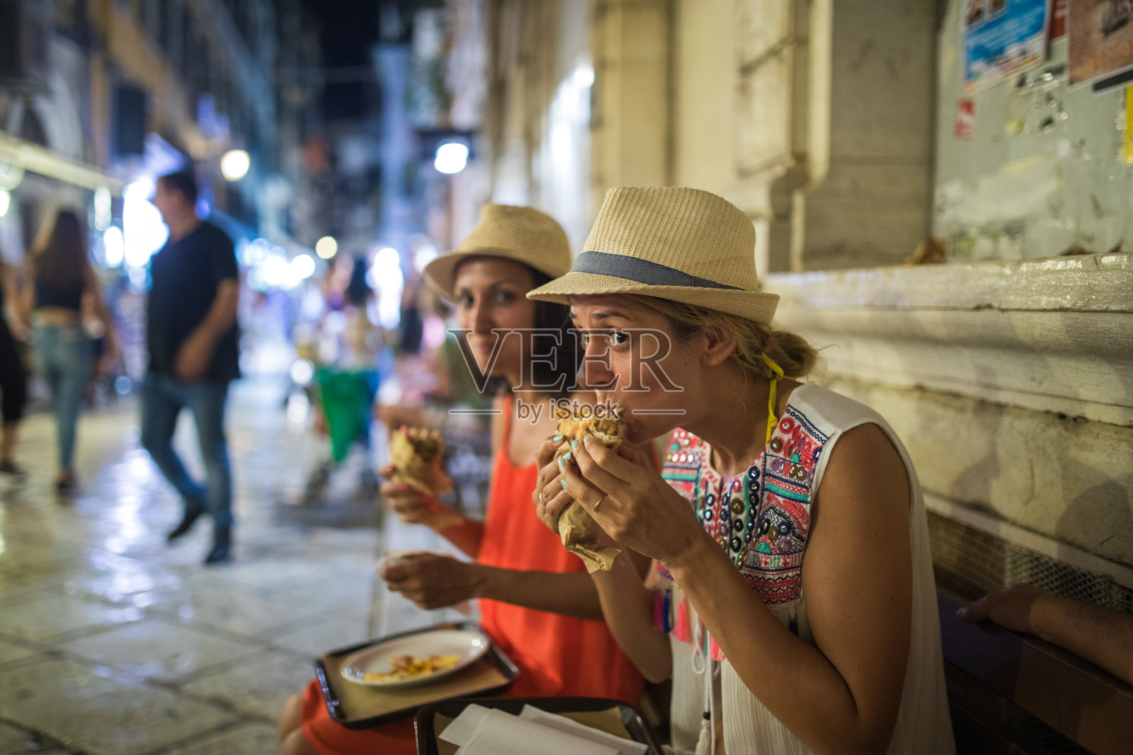 在科孚镇，饥饿的年轻游客正在吃吉洛斯照片摄影图片