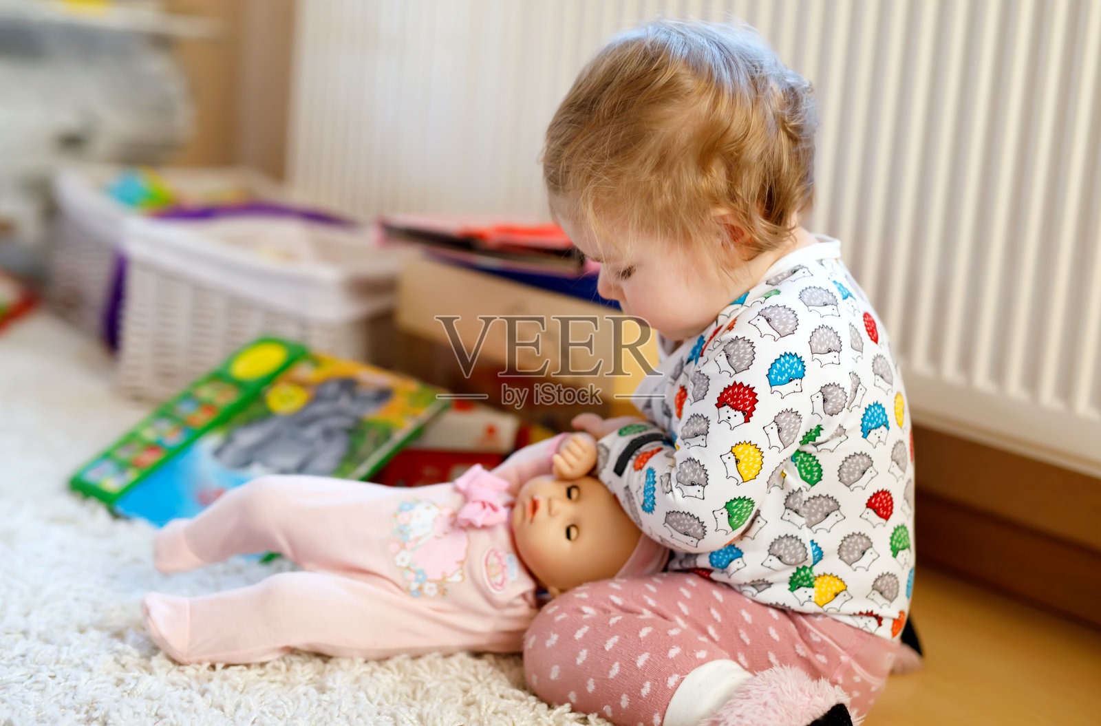可爱可爱的小女孩第一个玩娃娃。漂亮的蹒跚学步的孩子在家。照片摄影图片