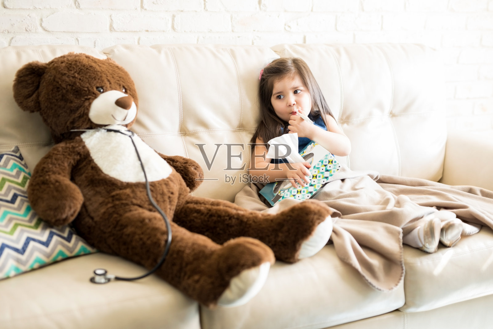 生病的女孩和泰迪熊医生在沙发上照片摄影图片