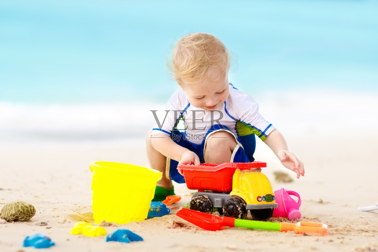 孩子们在热带海滩上玩耍。沙子和水玩具。照片摄影图片