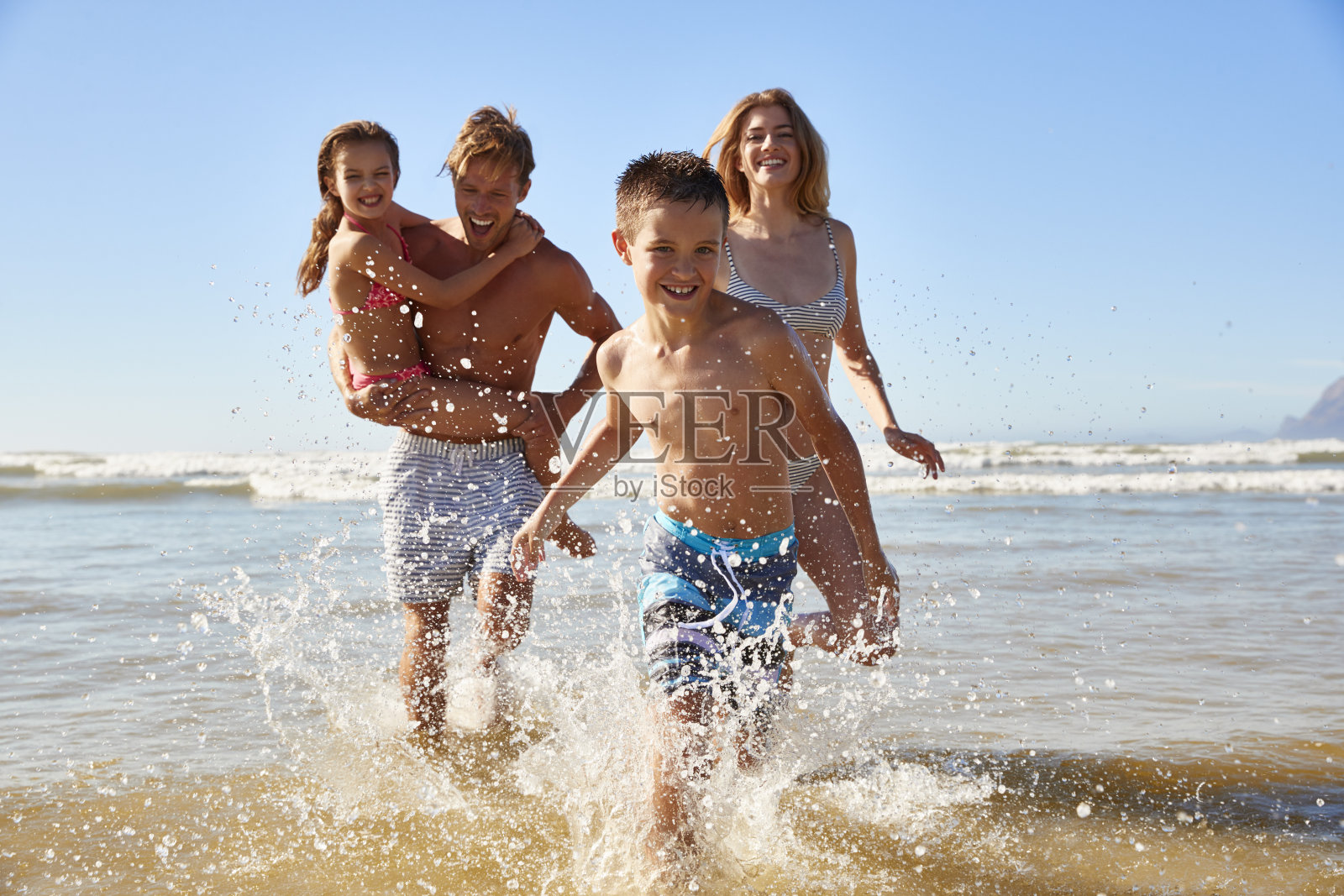 一家人在夏天的海滩度假跑出大海对着相机照片摄影图片