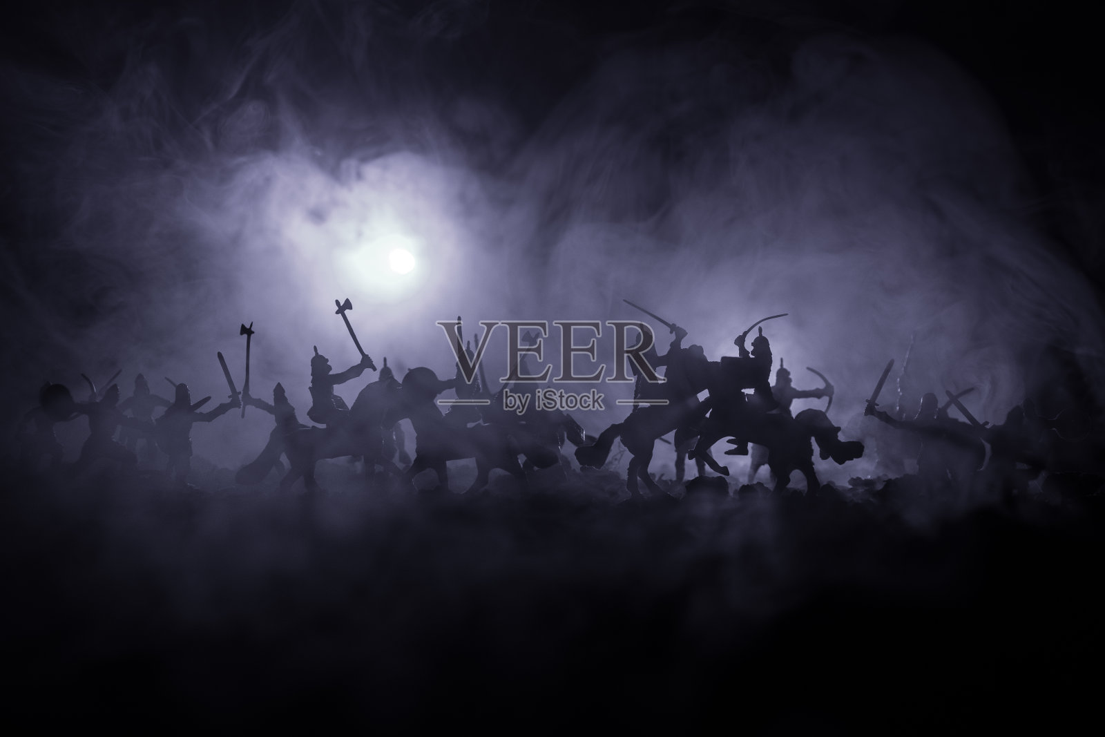 有骑兵和步兵的中世纪战斗场景。剪影的人物作为单独的对象，战斗的战士之间的黑暗色调的雾背景。夜景。照片摄影图片