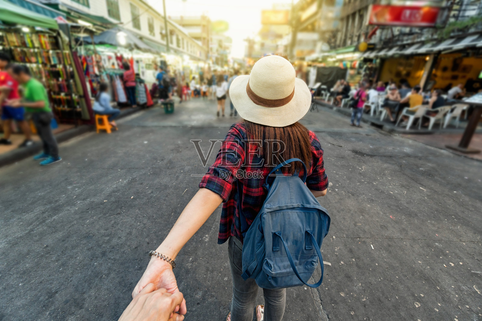 年轻的亚洲旅行女性牵着她的男朋友的手在晚上在泰国曼谷考山路步行街，一起旅行和游客跟我的概念照片摄影图片