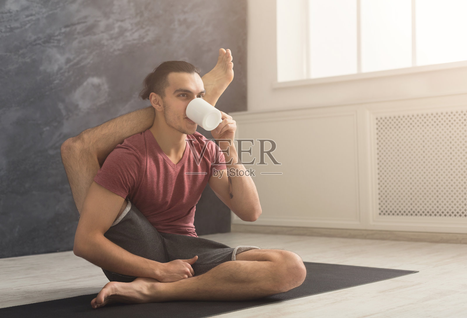 年轻人在柔韧的瑜伽姿势喝茶照片摄影图片