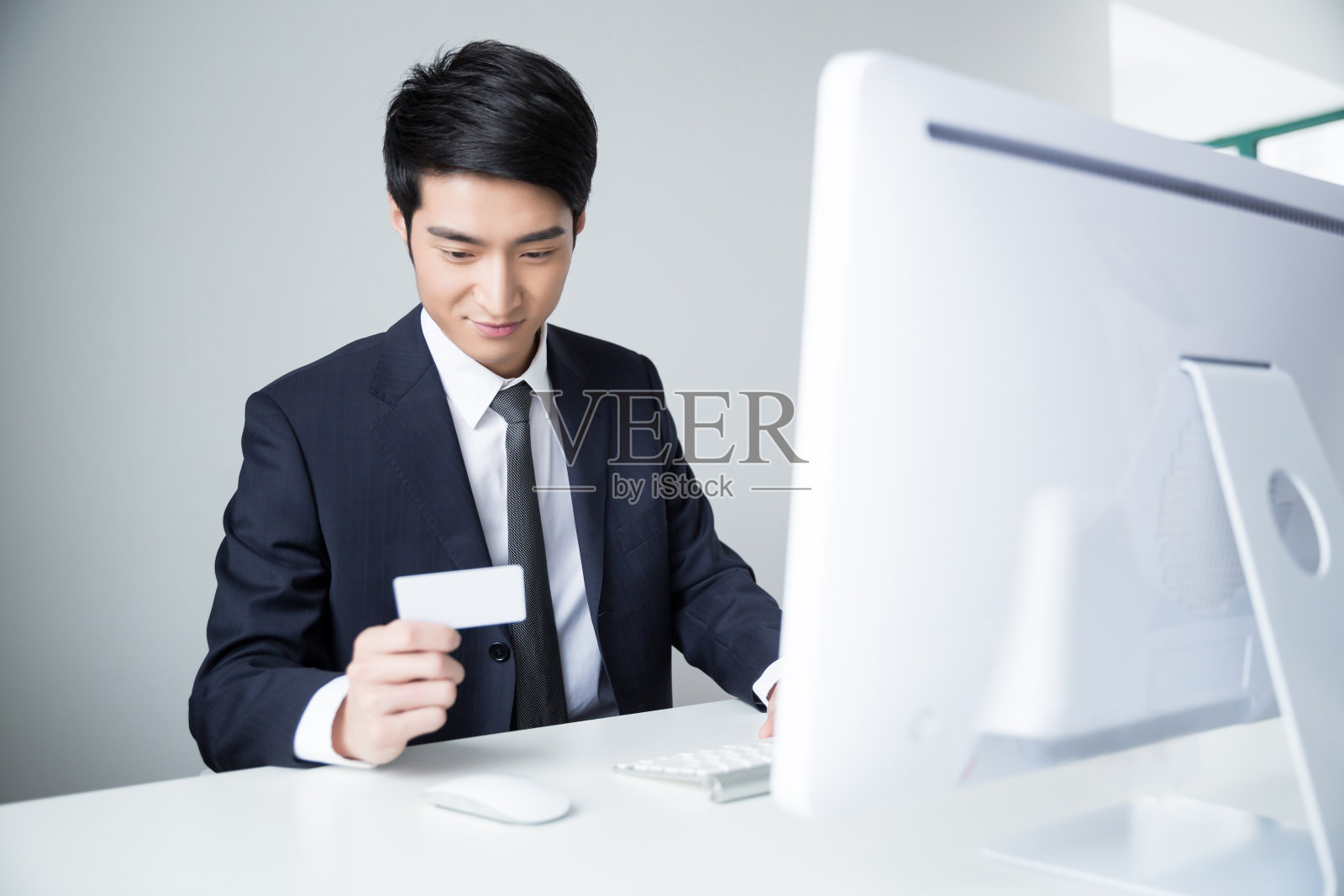 拿着信用卡在电脑上工作的年轻人照片摄影图片