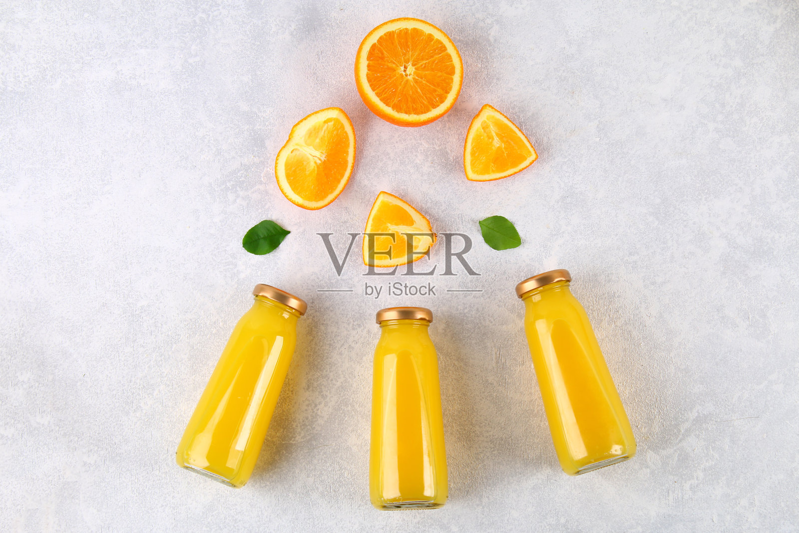 浅灰色的桌子上放着装着新鲜橙汁、橙片和黄色管的玻璃瓶。前视图。平的。照片摄影图片