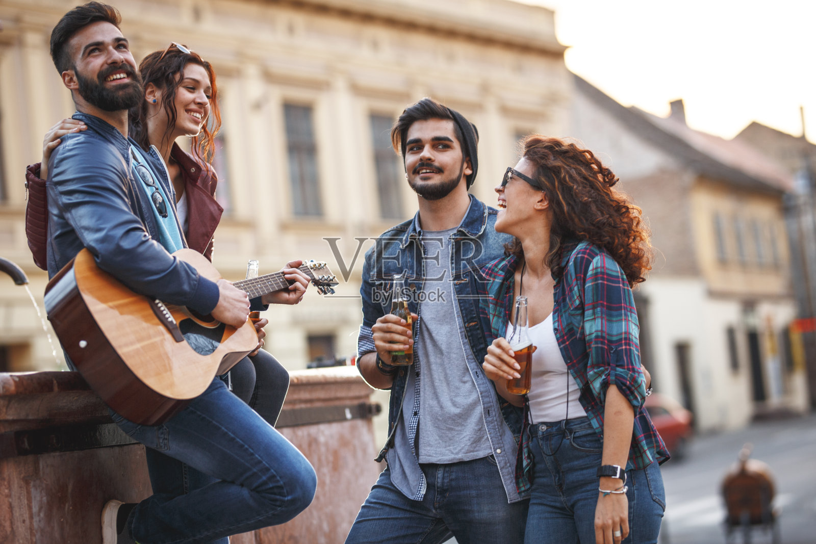 一群年轻人在城市广场上玩，他们弹吉他唱歌。照片摄影图片