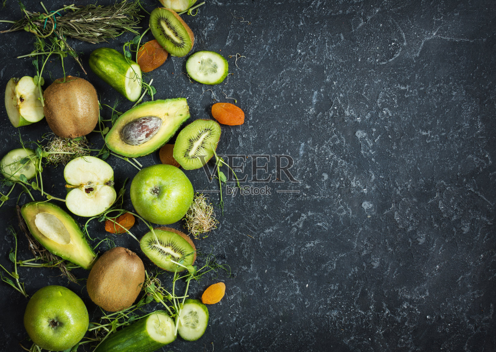 制作冰沙的配料。有机绿色蔬菜和水果在黑色的石头背景。拷贝空间，俯视图照片摄影图片