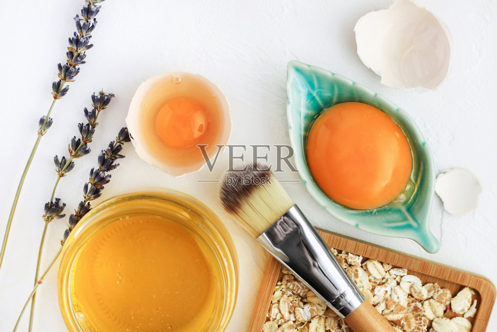 明亮的蛋黄，燕麦片，蜂蜜，薰衣草与化妆刷特写，天然整体成分自制美容护理。照片摄影图片