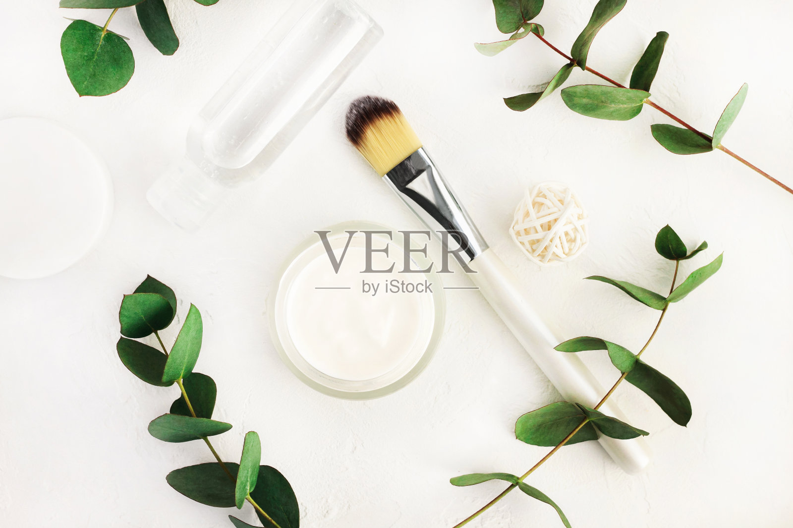 草药治疗护肤品。瓶化妆品保湿和面部补液瓶与新鲜桉树枝。简单的白色和绿色照片摄影图片
