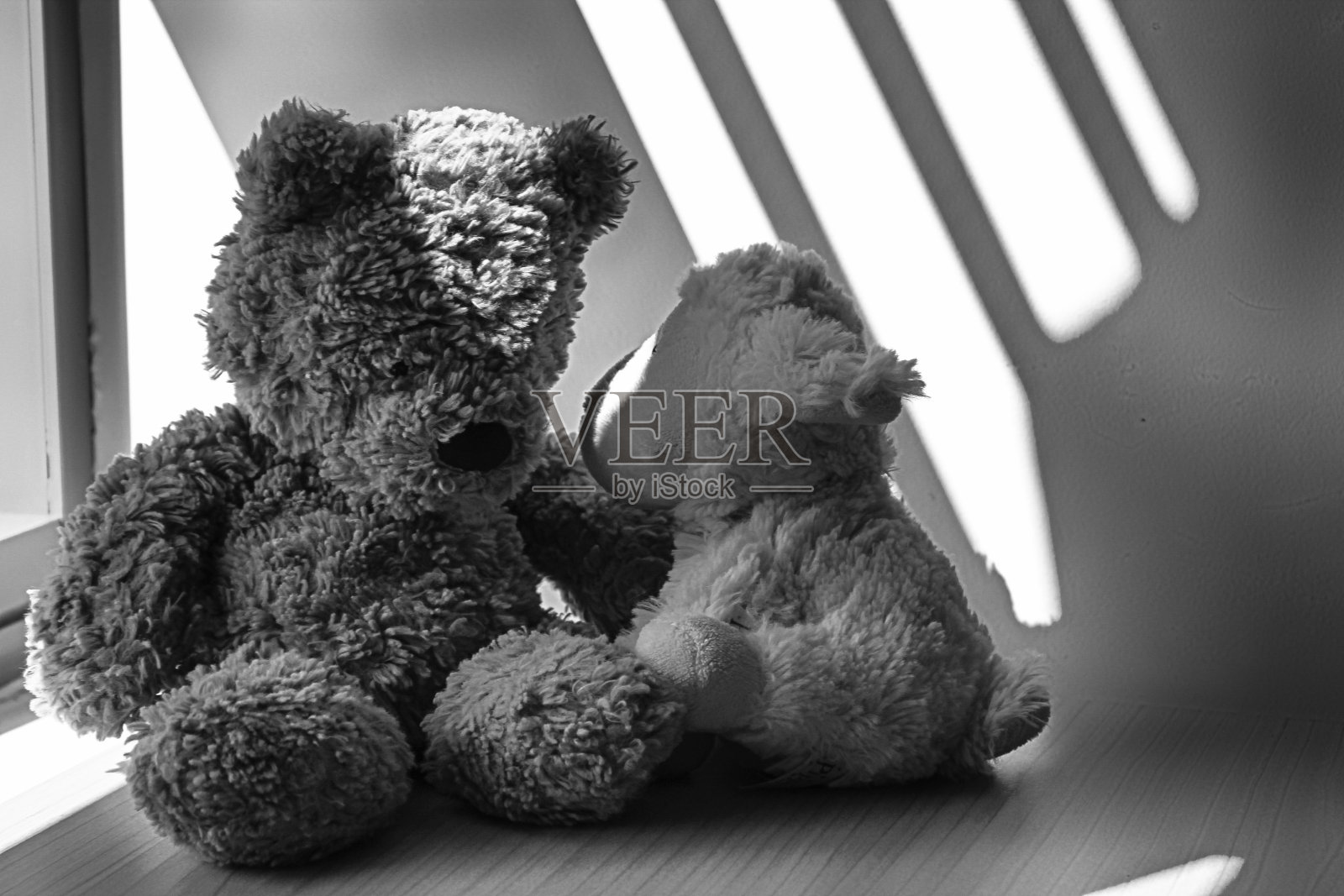 黑白小熊和小羊玩具坐在窗边的阴影里照片摄影图片