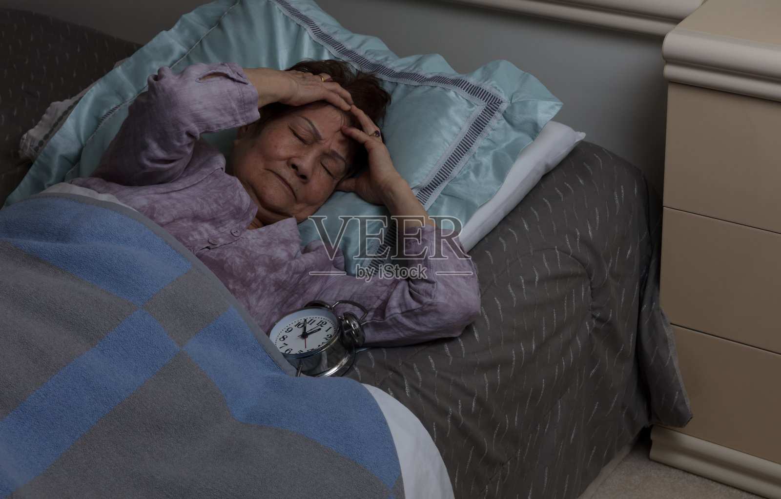 老年妇女夜间在床上时头痛照片摄影图片