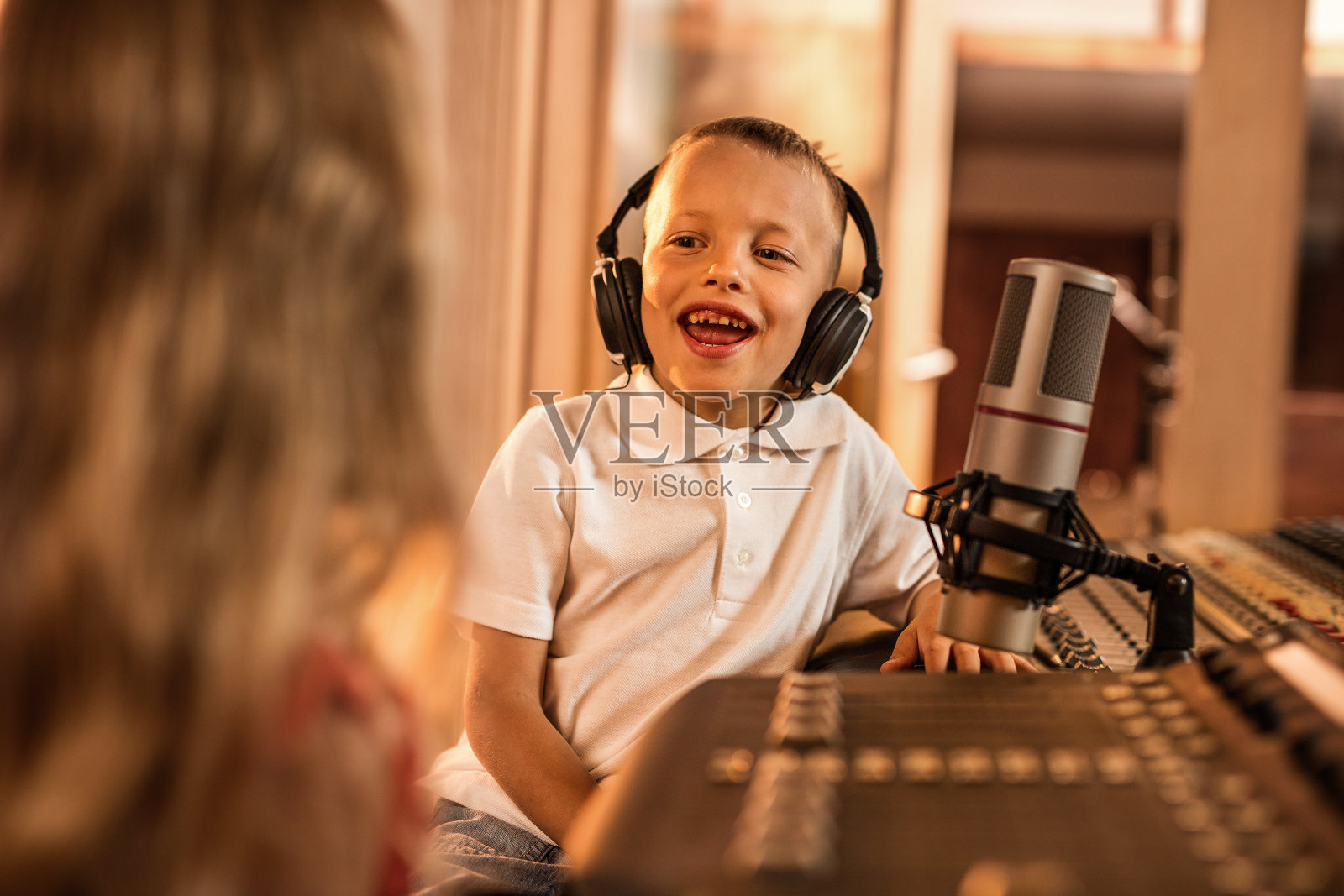 一个微笑的小男孩和他的客人在广播演播室。照片摄影图片