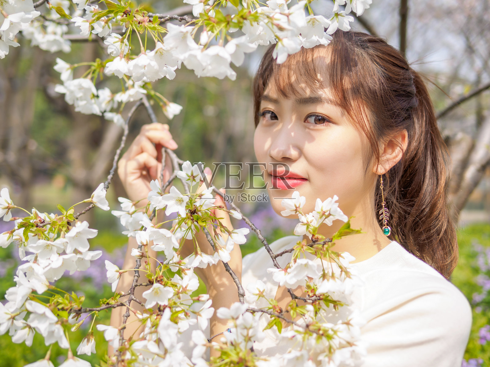 户外肖像美丽的年轻中国女孩微笑在盛开的樱花树早午餐在春天的花园，美丽，夏天，情感，表达和人们的概念。照片摄影图片