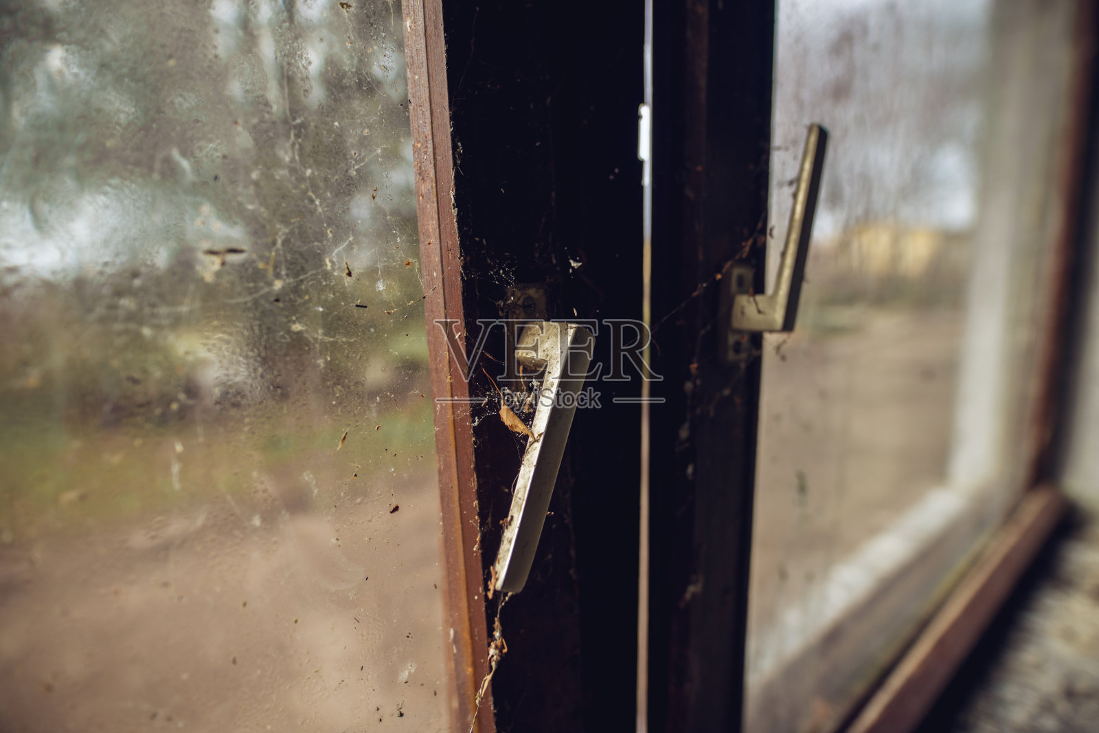 在废弃的废弃的房子里，被遗忘的破窗和蜘蛛网的近距离聚焦视图。照片摄影图片