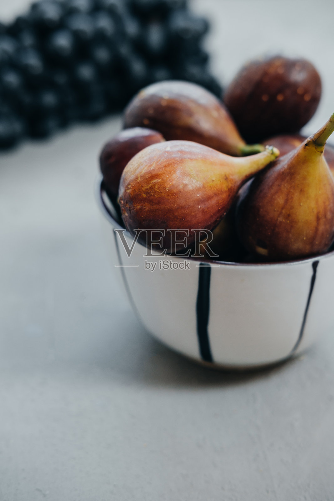 碗里的无花果和灰色背景上的深色葡萄。秋天的收获照片摄影图片