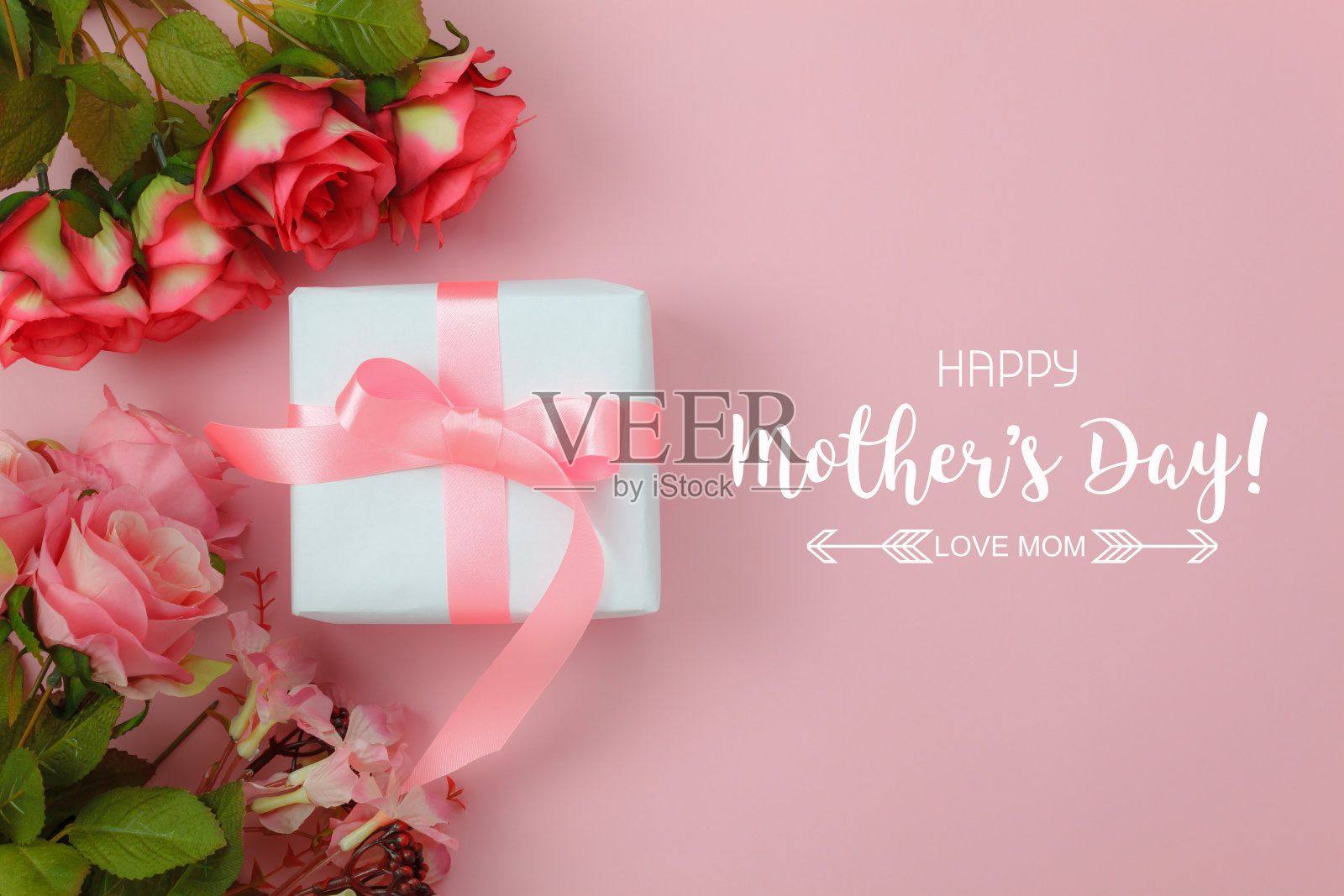 俯视图航拍装饰母亲节节日背景概念。平铺白色礼盒与红玫瑰在现代美丽的粉红色纸在家庭办公书桌。为设计文本预留空间。照片摄影图片