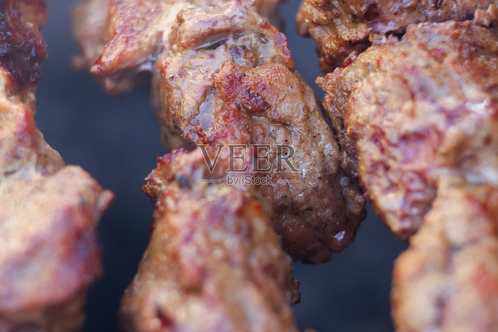 鲜美多汁的肉块，用木炭烤架烤串。把肉靠近点烤照片摄影图片