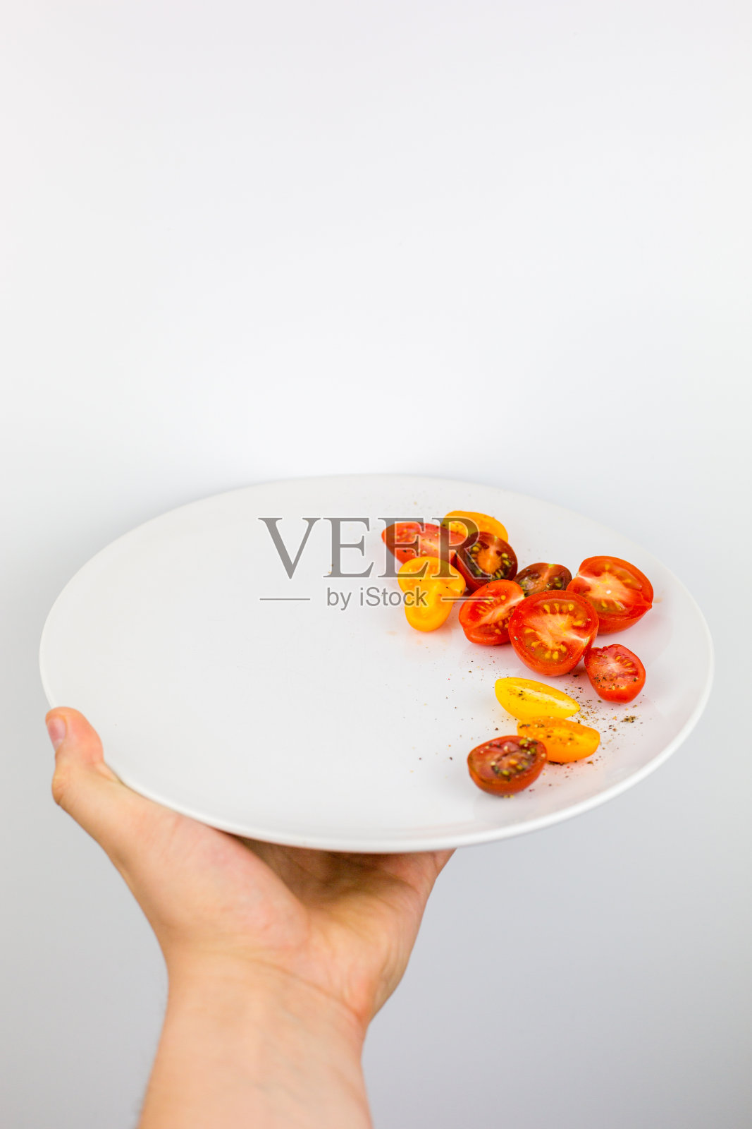 孤立的手持盘子与切好的番茄照片摄影图片