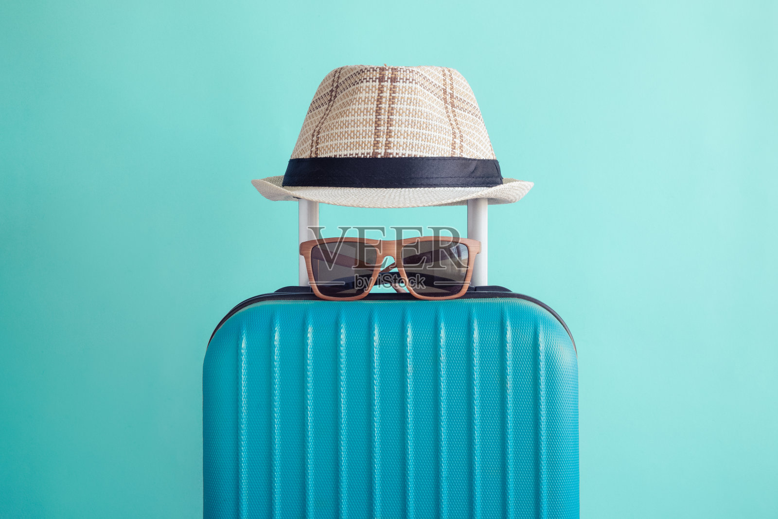 行李箱与编织的海滩帽和太阳镜在绿色的背景简约的度假概念照片摄影图片