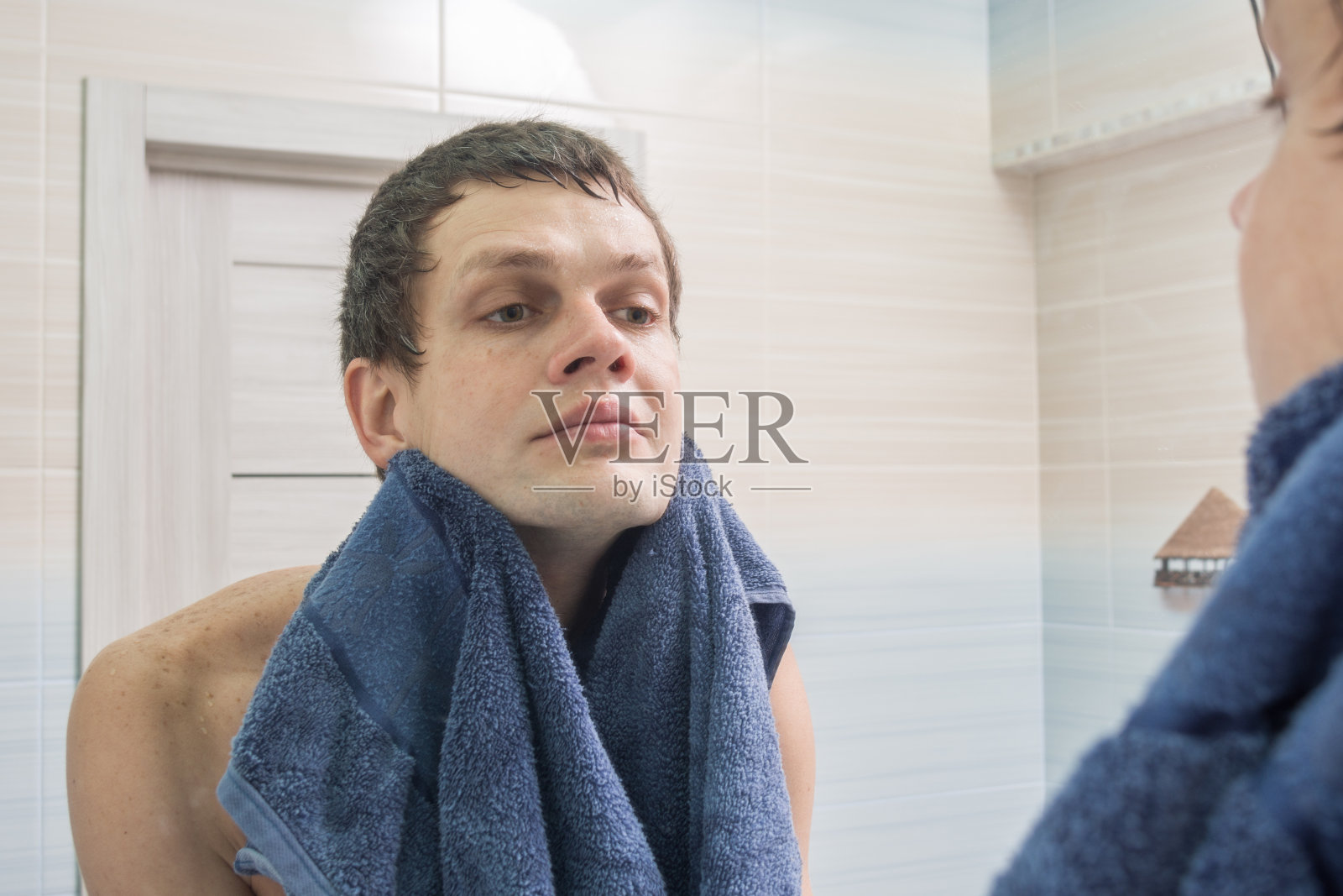 一个年轻人刮了脸，洗了脸，用毛巾擦干身子照片摄影图片