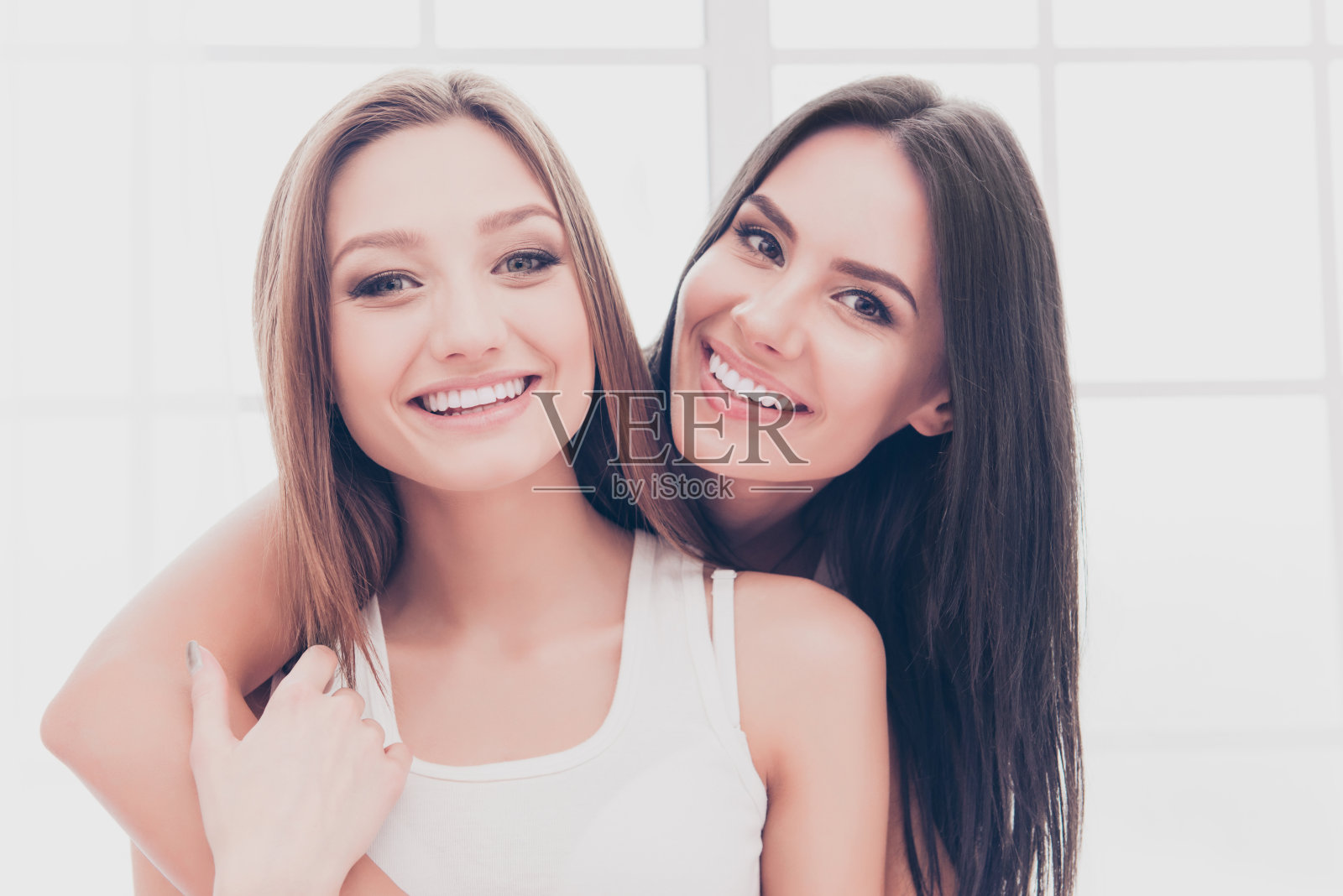 两个美丽开朗的女孩微笑着拥抱的肖像照片摄影图片