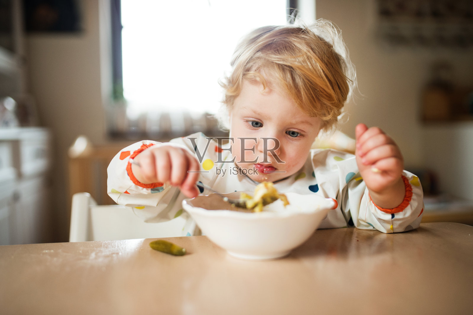 一个蹒跚学步的男孩在家吃饭。照片摄影图片