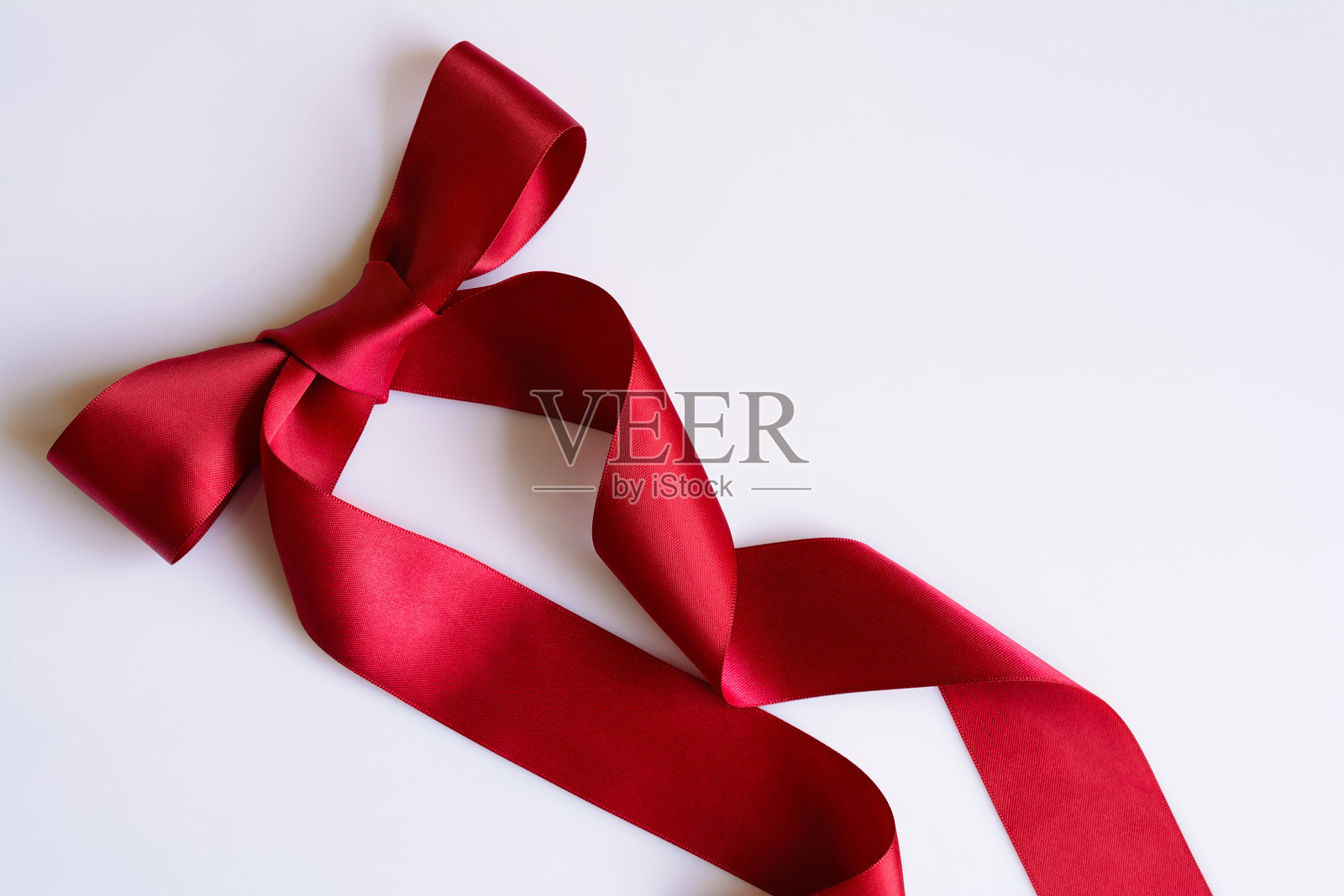 闪亮的装饰红色缎带与蝴蝶结在白色的背景。猩红色胶带，设计元素。照片摄影图片