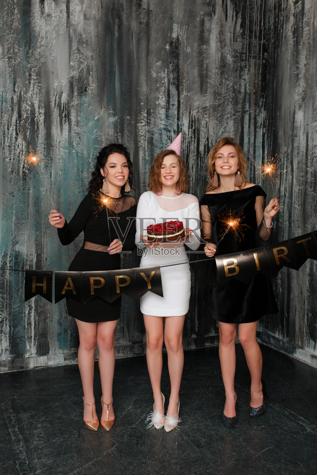 年轻迷人的白人女人与生日蛋糕在她的朋友与派对火花。庆祝的人们的肖像。室内照片摄影图片