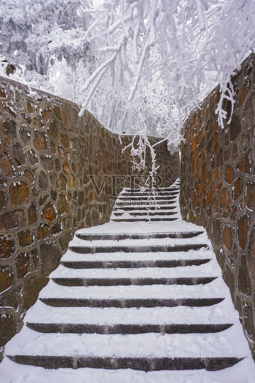 他的楼梯被雪覆盖着，由石墙支撑着照片摄影图片