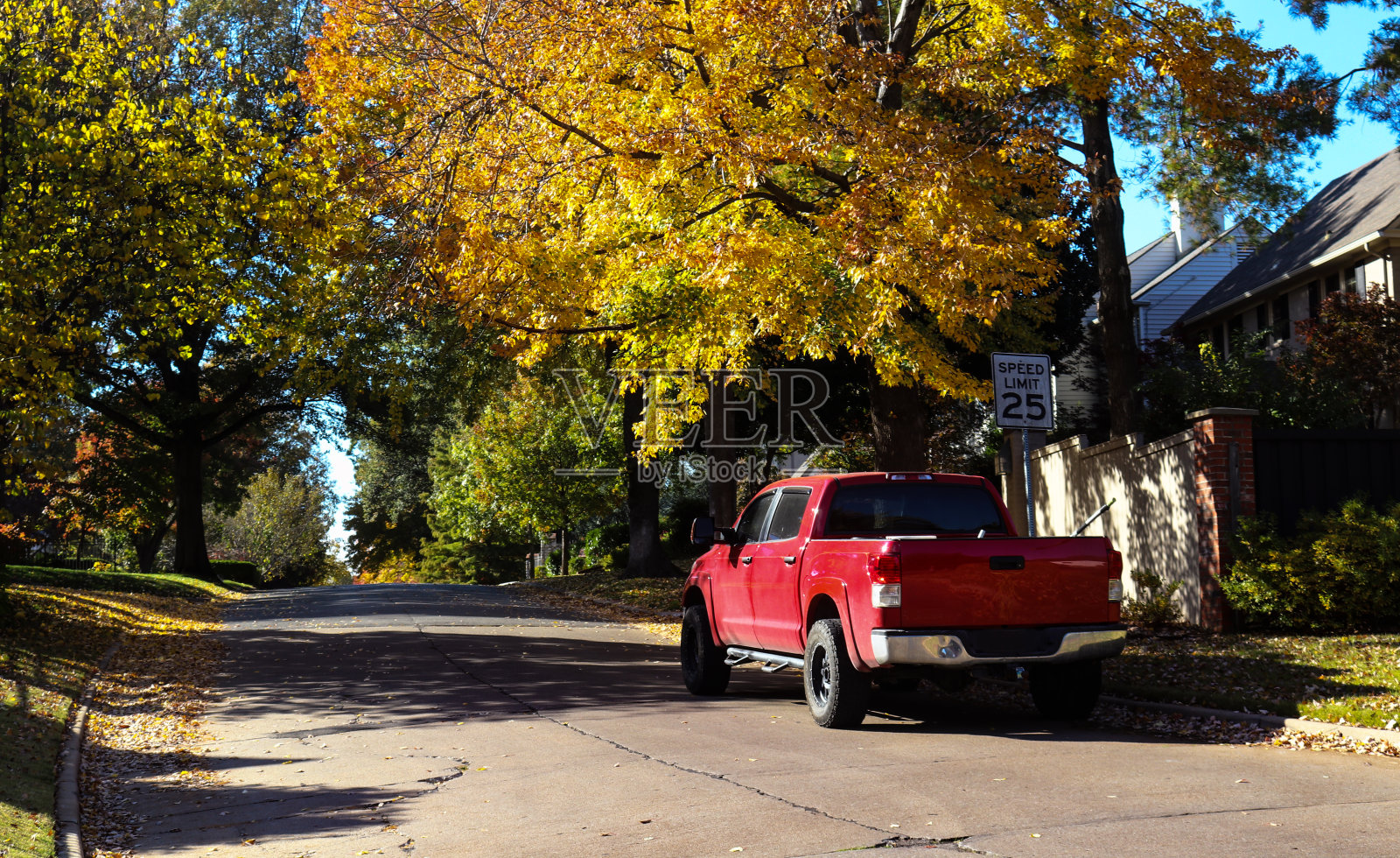 秋天，一辆红色的皮卡停在绿树成荫的社区街道上照片摄影图片