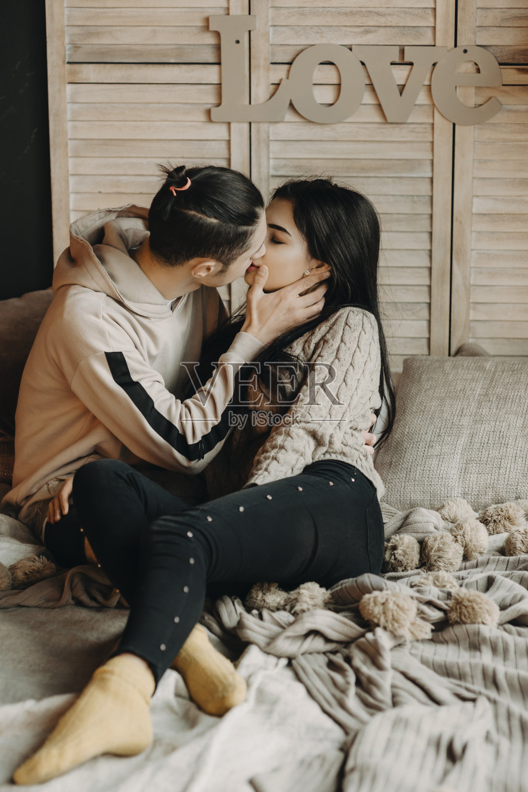 一对美丽的年轻夫妇躺在床上，男人温柔地亲吻着他的女人。照片摄影图片