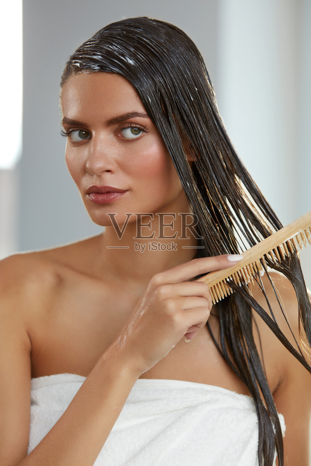 美丽的女人在长湿头发上敷面膜。毛刷照片摄影图片
