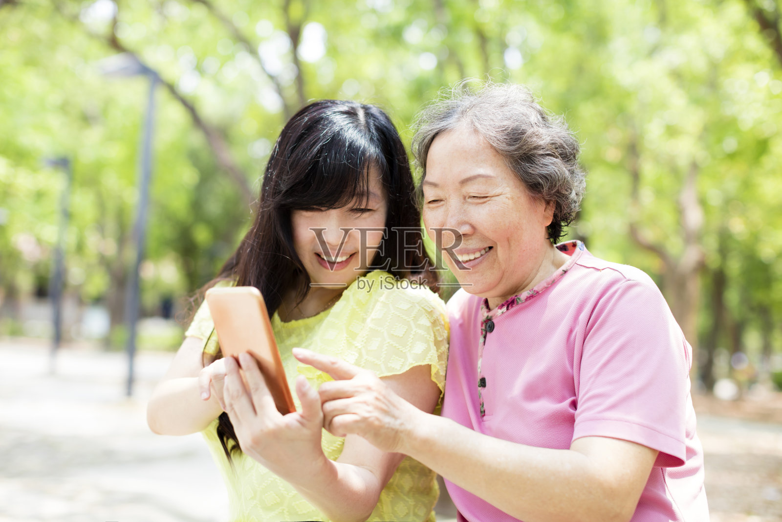 快乐的老妈妈和女儿看智能手机照片摄影图片