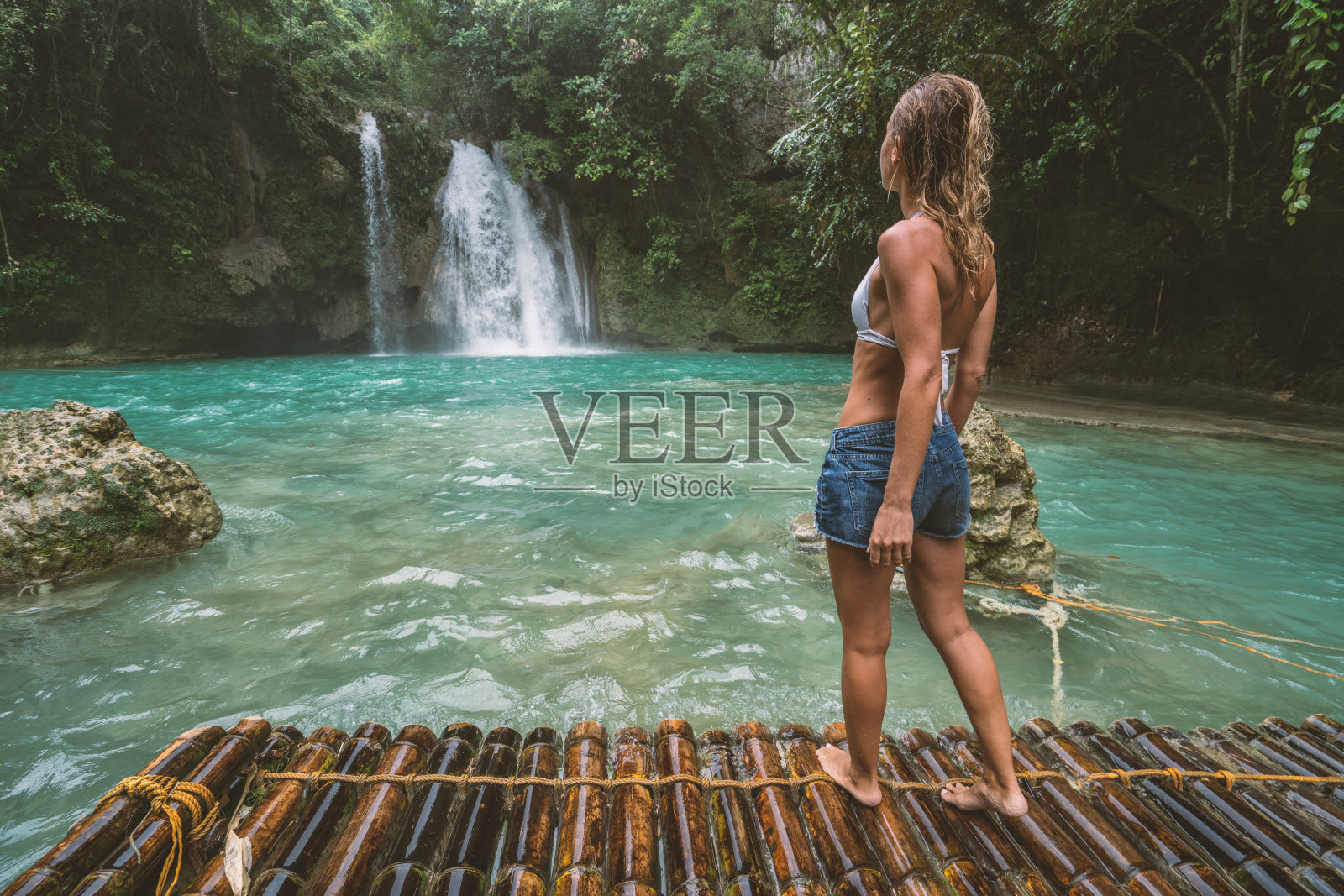 年轻女子凝视美丽的瀑布竹筏，菲律宾照片摄影图片