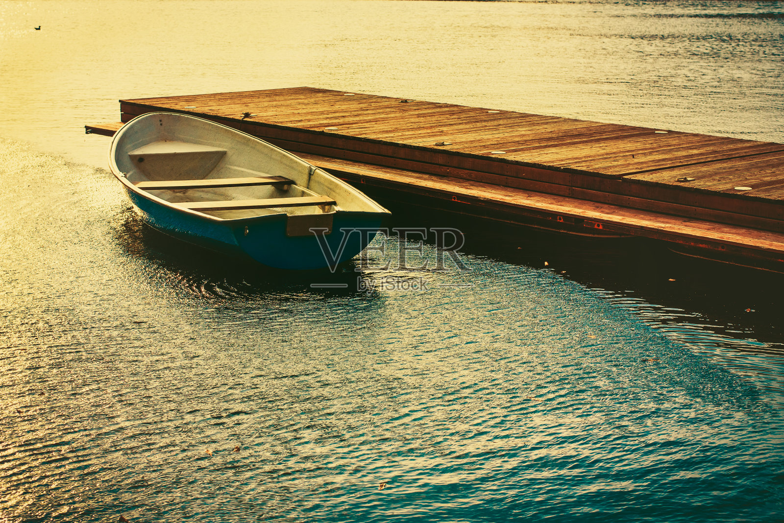 日落时分，一艘小船系在湖上的木码头上照片摄影图片