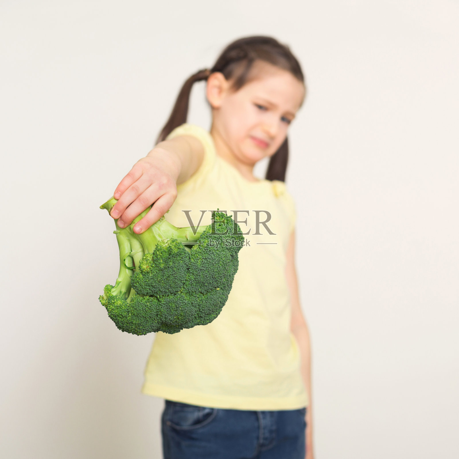 恶心的小女孩用花椰菜盖着白色的背景照片摄影图片