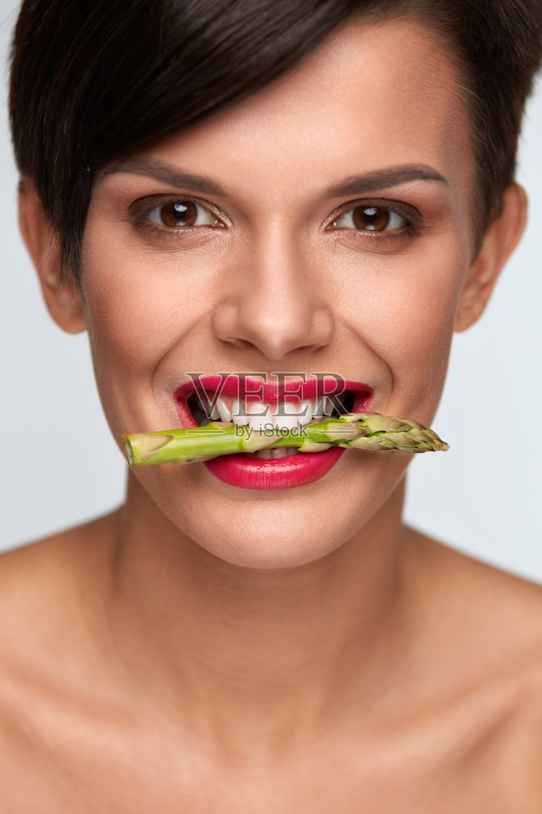 健康饮食。用牙齿夹着芦笋的美女照片摄影图片