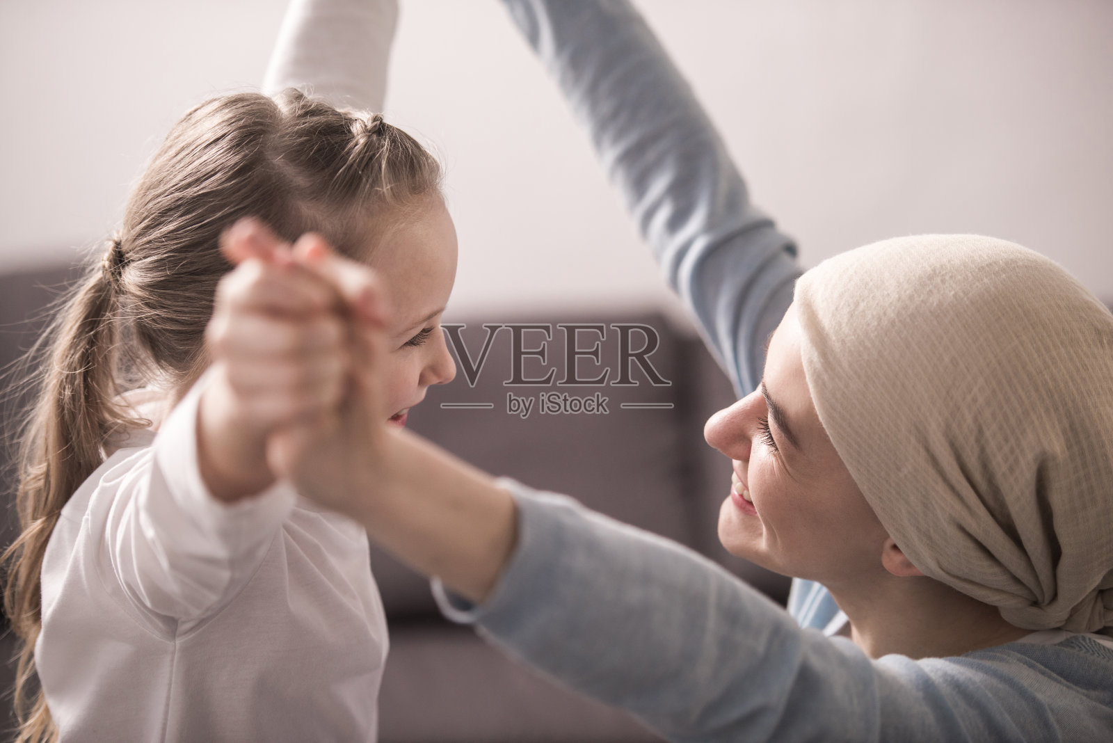 快乐的孩子和生病的母亲在头巾里牵着手，彼此微笑照片摄影图片