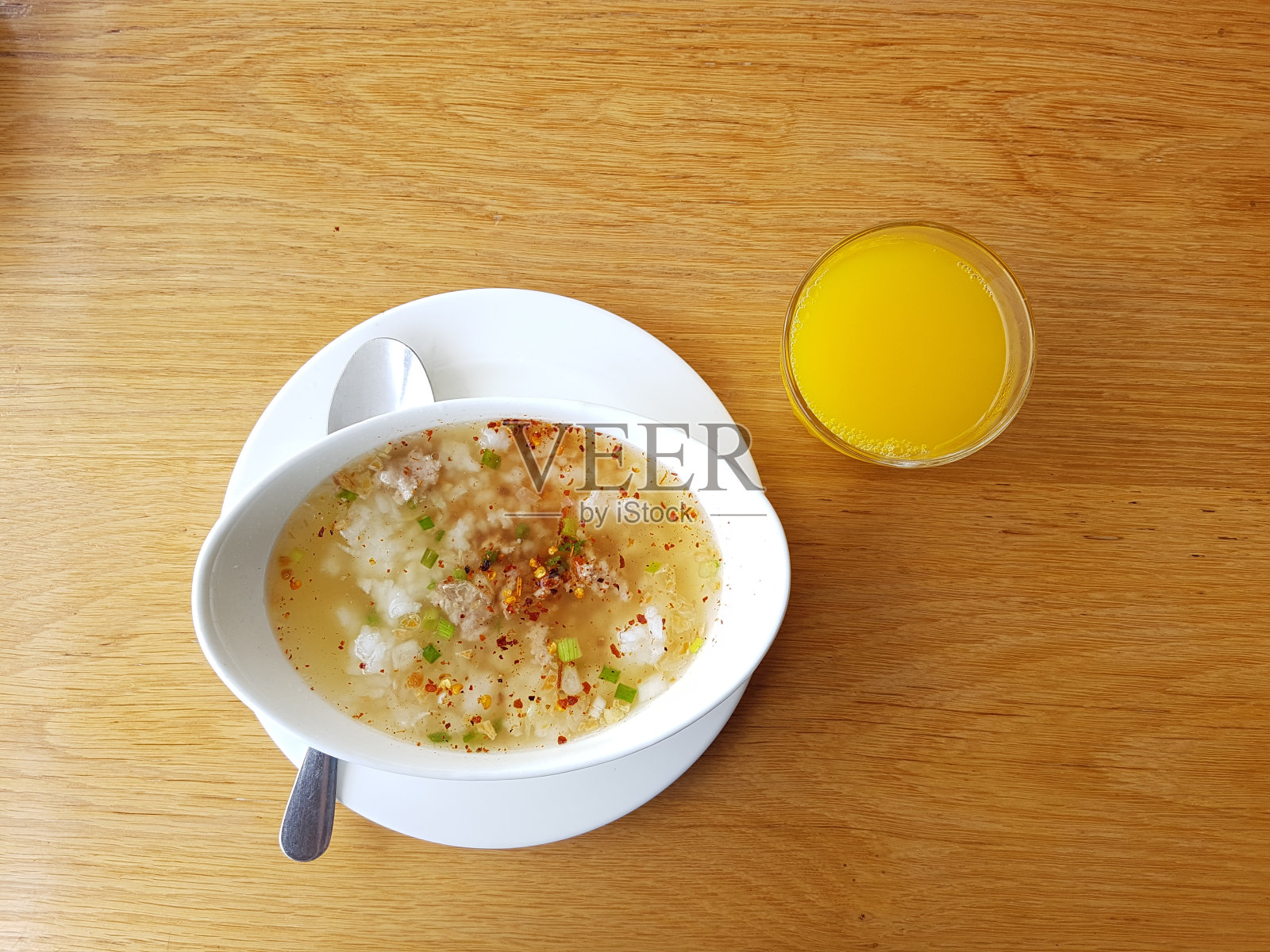 米饭猪肉煮早餐，橙汁和饮用水在木头桌子上。(亚洲传统食物)照片摄影图片
